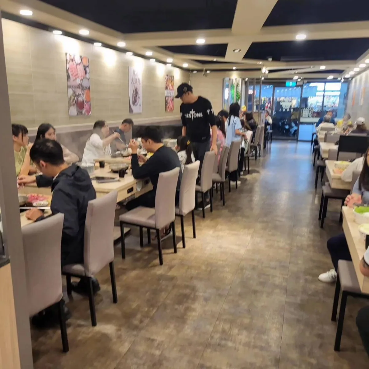 用餐時段裡坐滿客人的鍋物餐廳走道與兩側桌席